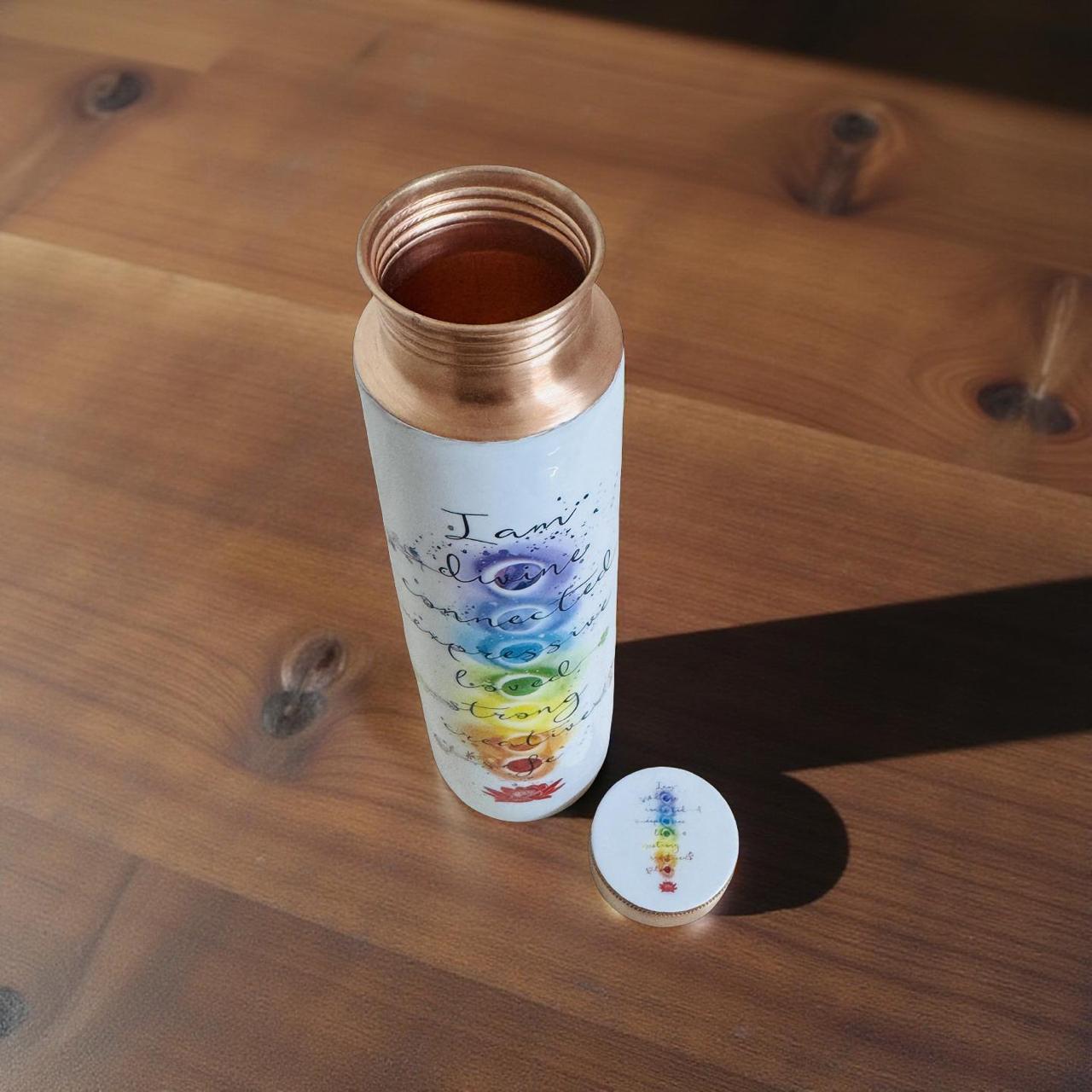 Copper-bound water bottle with chakra design on a wooden surface