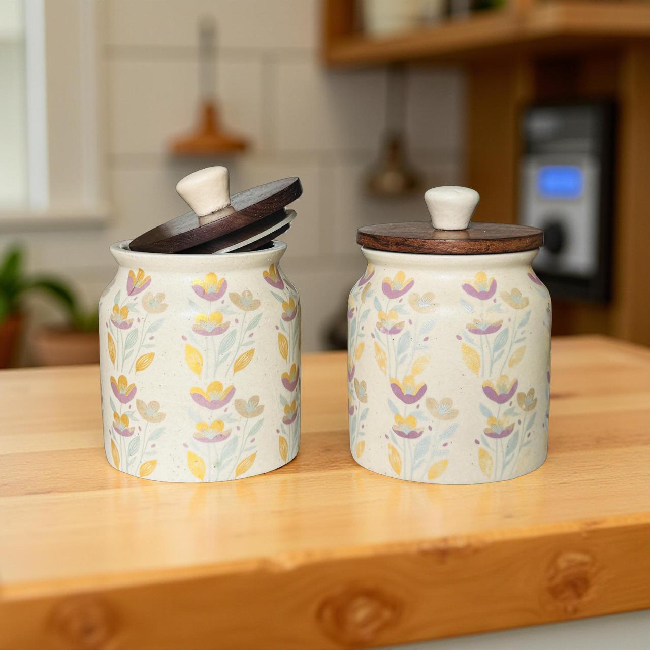 Two ceramic jars with floral patterns on a wooden surface in a kitchen setting.