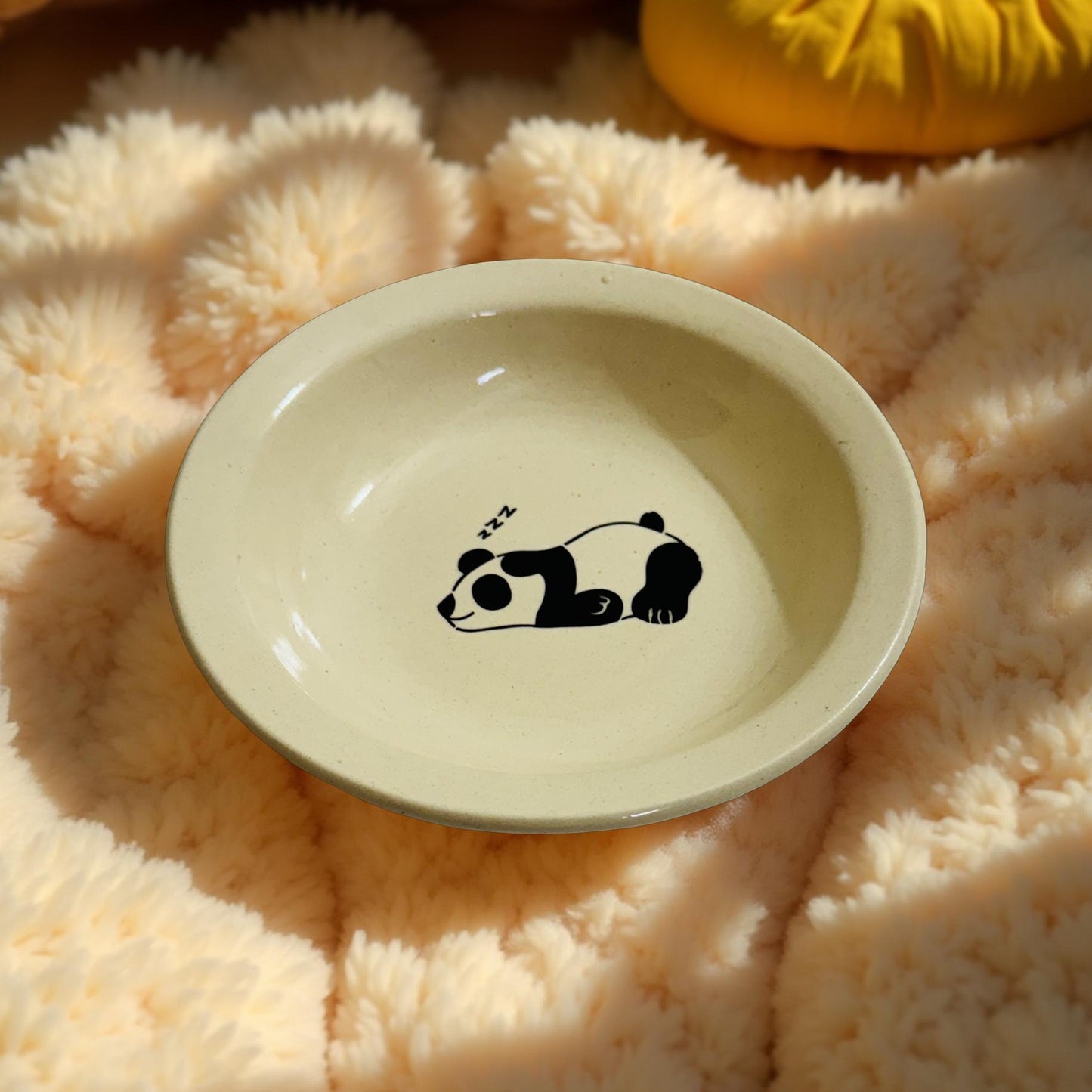 Beige ceramic dish with a panda design on a fluffy pink surface