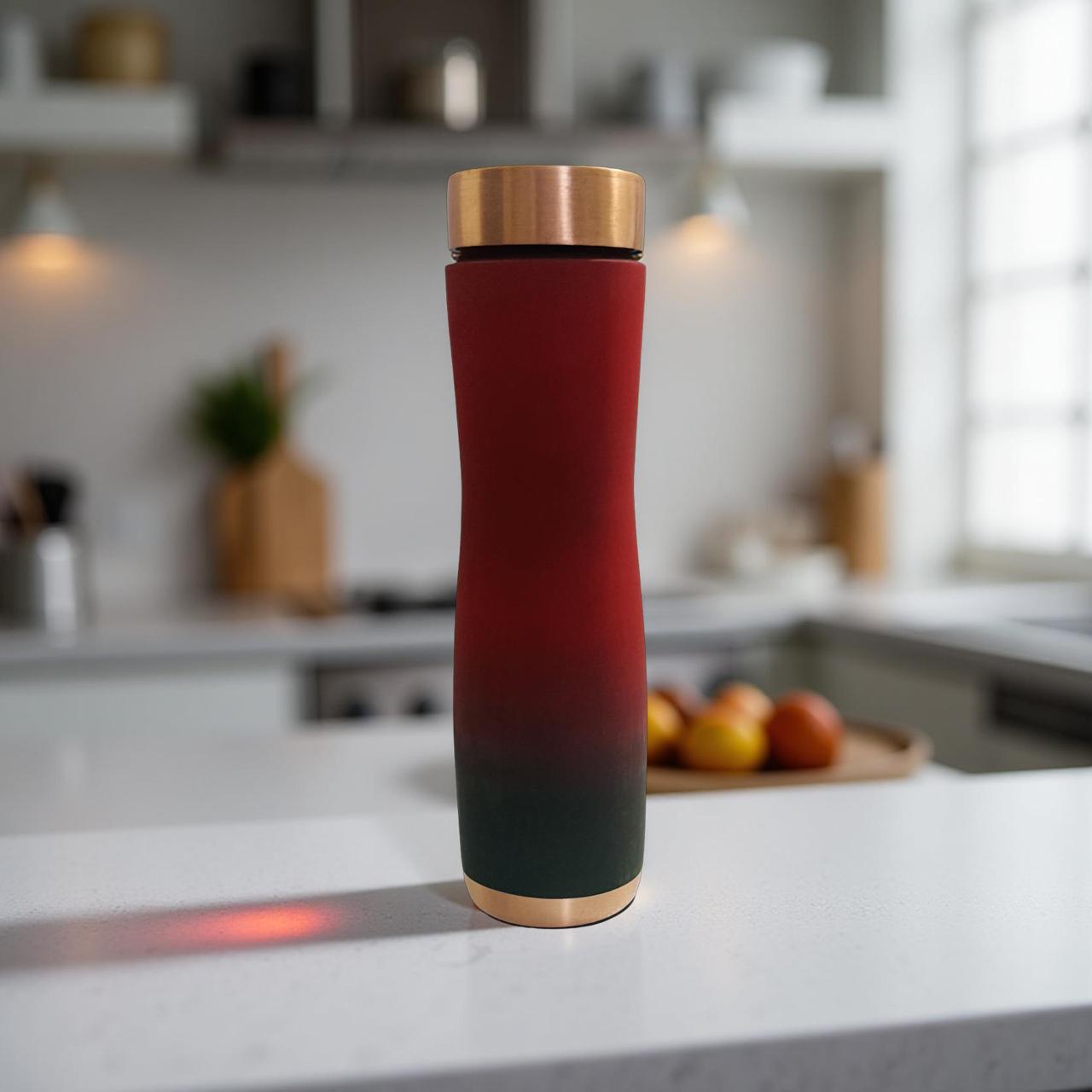 Red and black colour copper bottle with gold cap on a kitchen counter