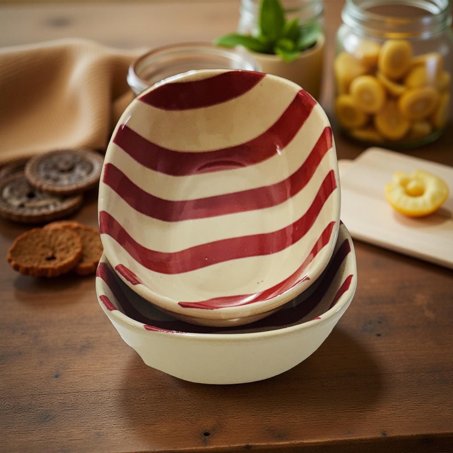 Stack of ceramic bowls with red and white stripes on a wooden surface