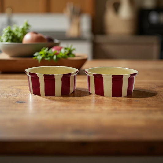 Two red and white striped ceramic bowls on a wooden surface with blurred kitchen background