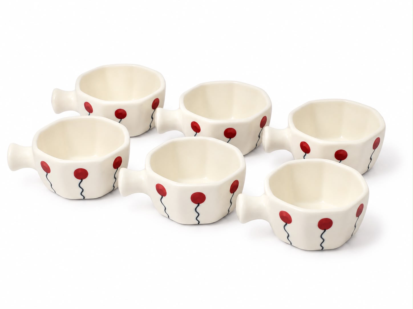 Six small white ceramic cups with handles, decorated with red balloon motifs and thin black wavy lines, arranged on a white background.