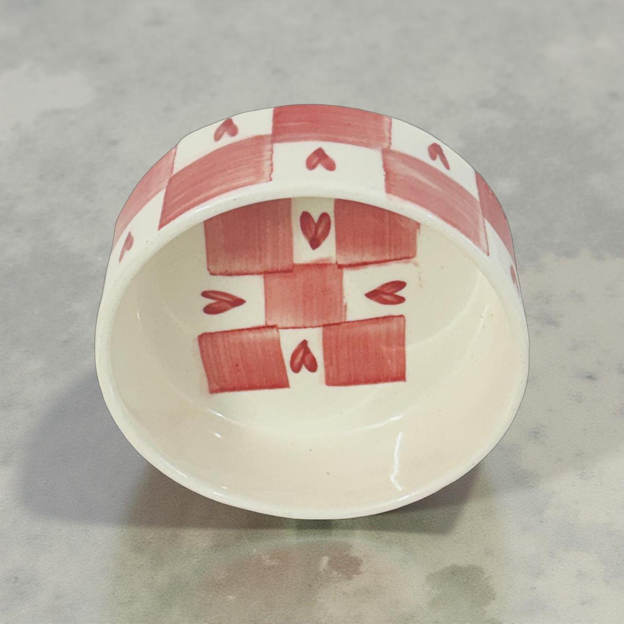Small ceramic bowl with red geometric pattern on a gray surface