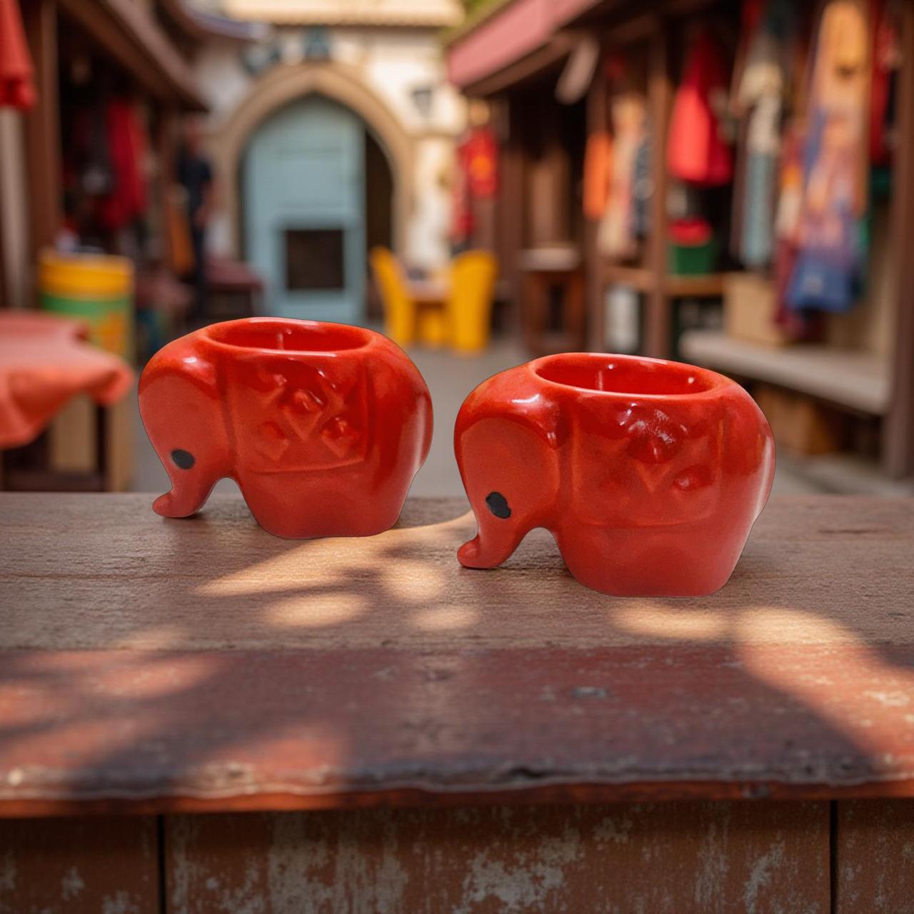 Two red elephant-shaped mugs on a wooden surface with a blurred background of a store.