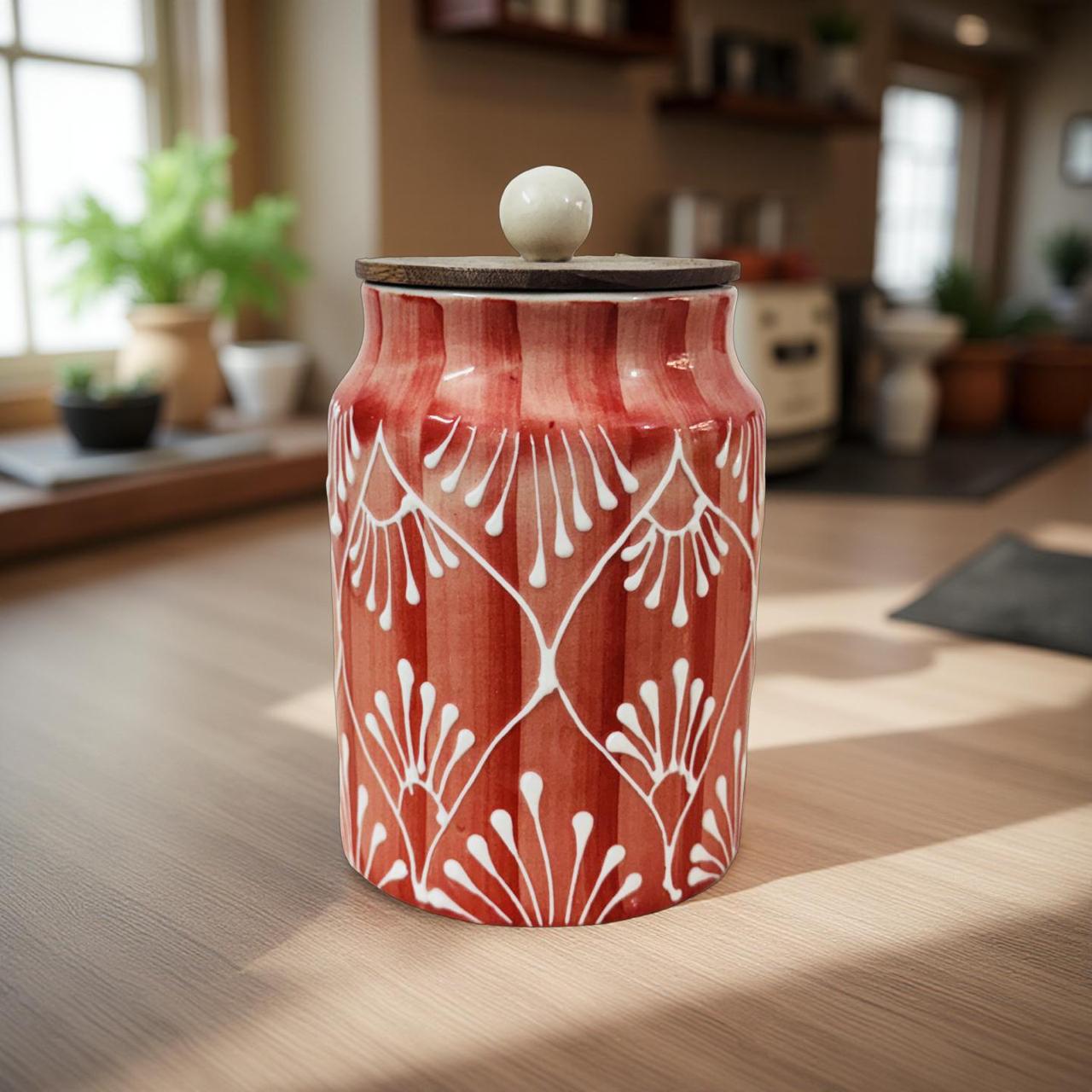 Decorative red ceramic jar with white patterns on a wooden floor in a home setting.