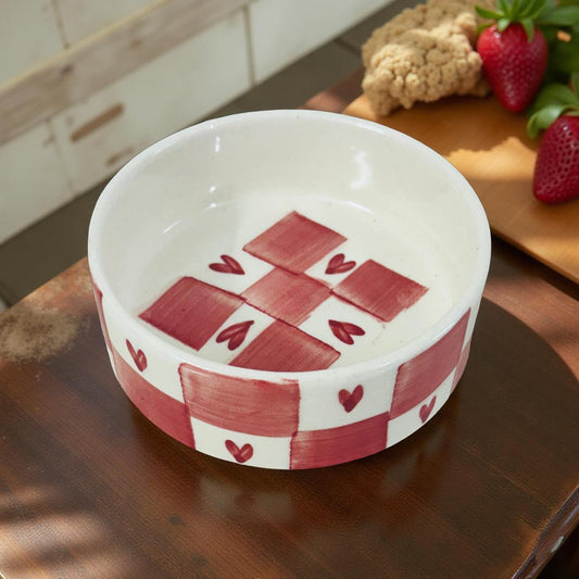 Ceramic bowl with red checkered pattern on a wooden surface