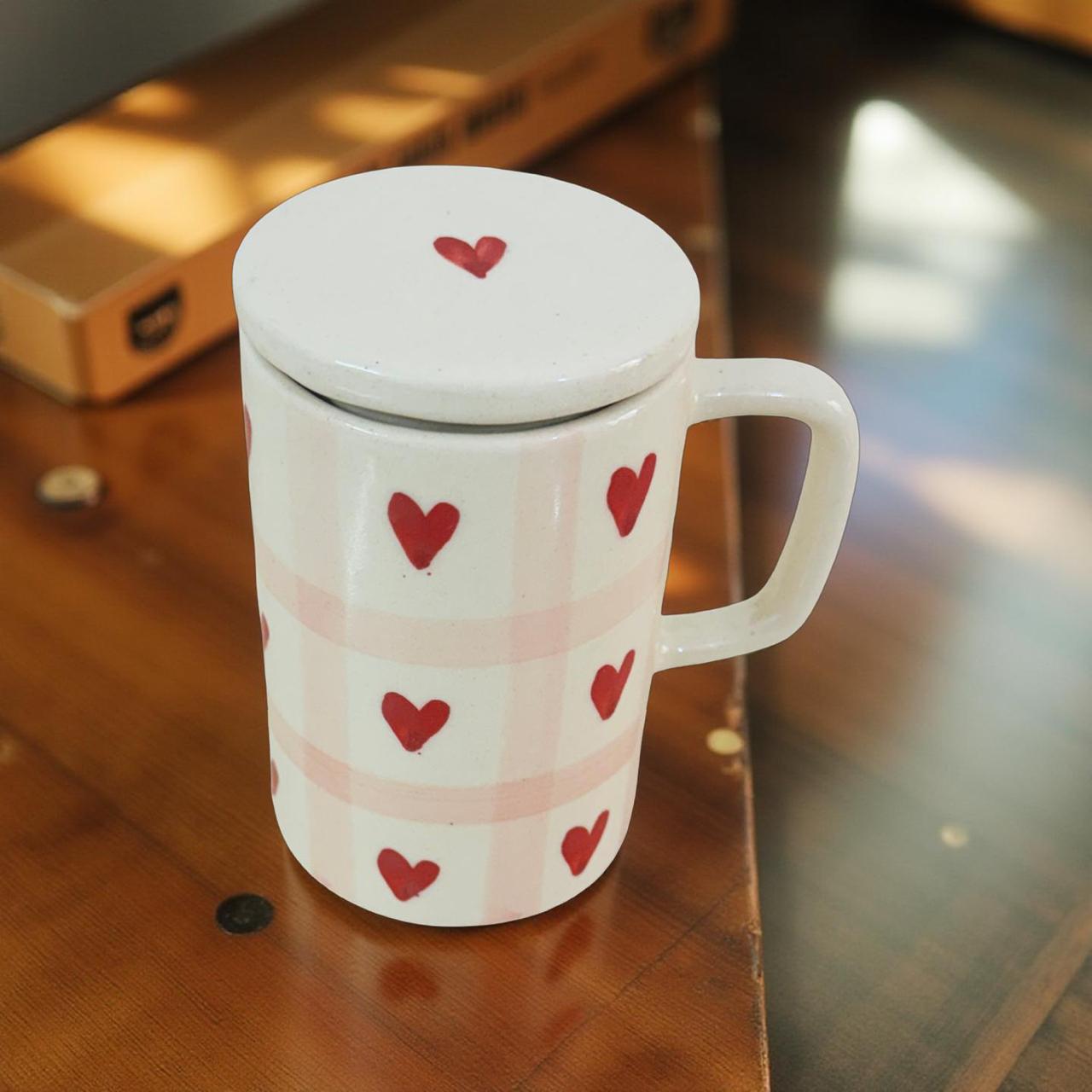 White mug with red heart patterns on a wooden surface