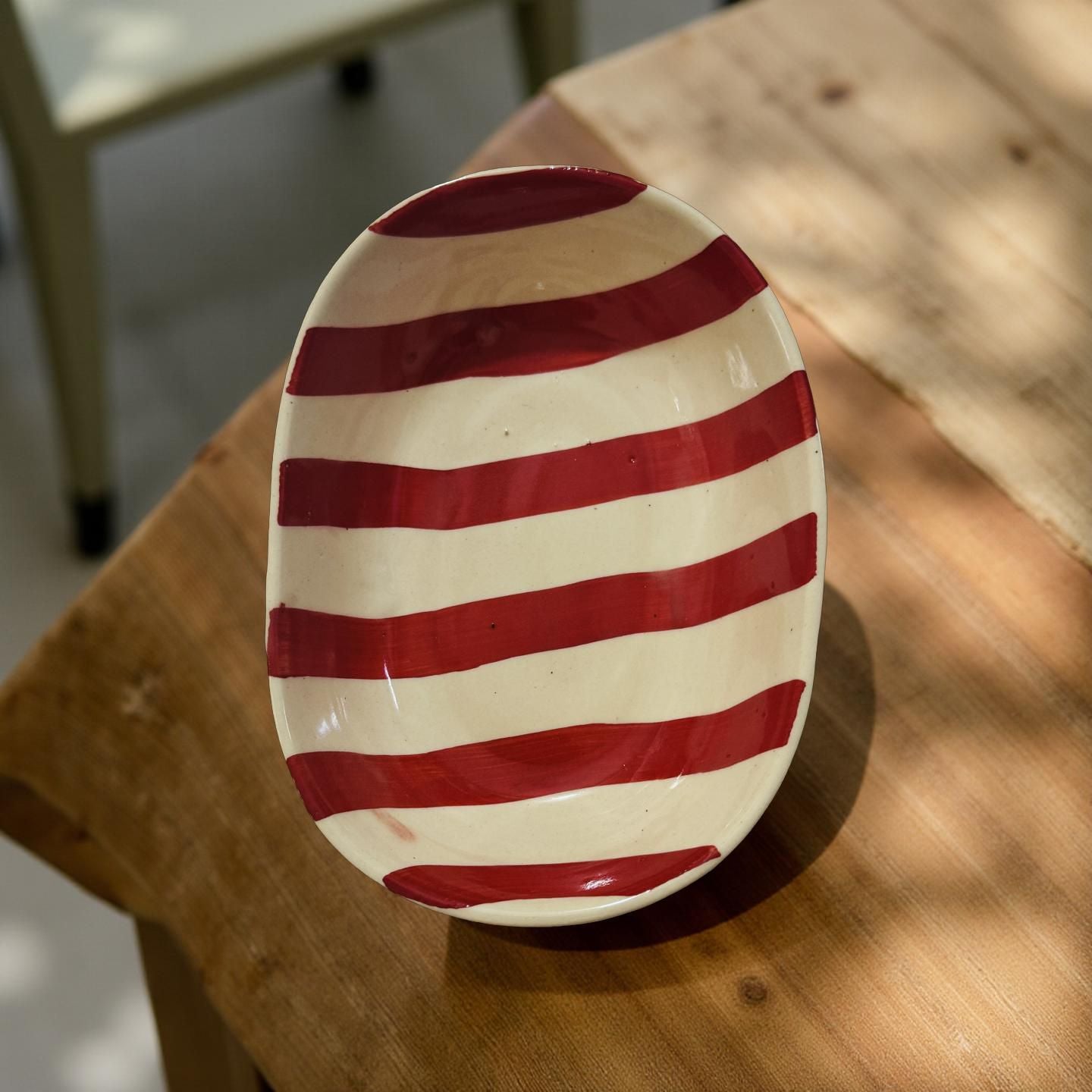 Ceramic plate with red and white stripes on a wooden surface