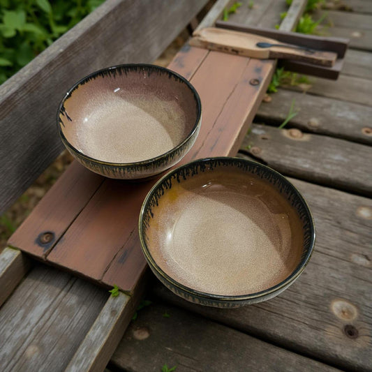 Two ceramic bowls on a wooden surface with a natural outdoor background