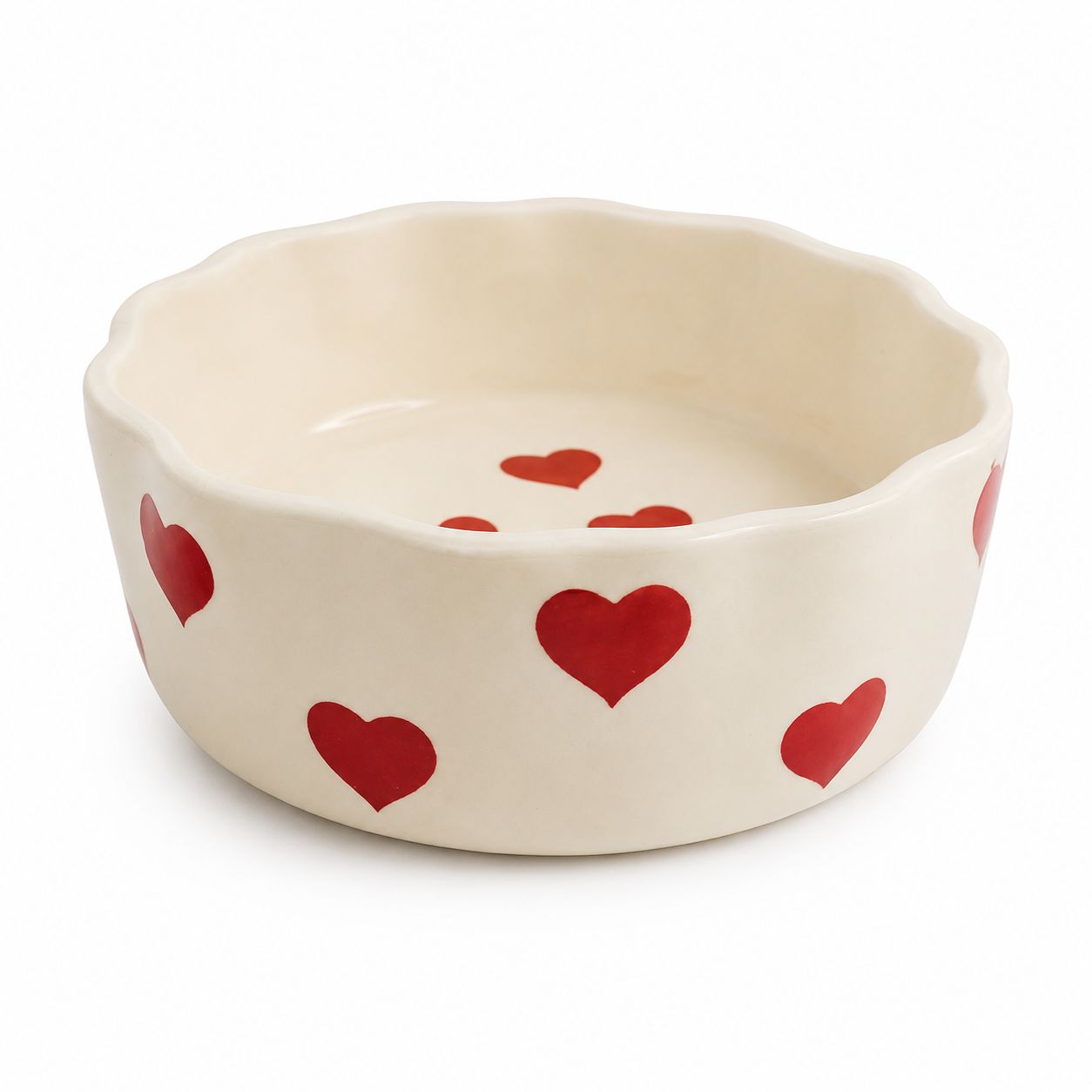 An off-white ceramic bowl with a scalloped rim, decorated with red hearts, shown on a plain white background.