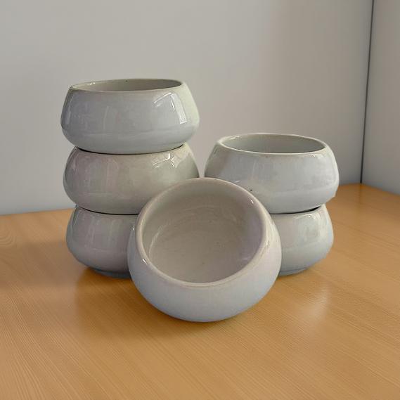 Set of white ceramic bowls on a wooden surface with a neutral background