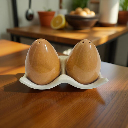 Two brown ceramic salt and pepper shakers on a matching holder on a wooden surface.