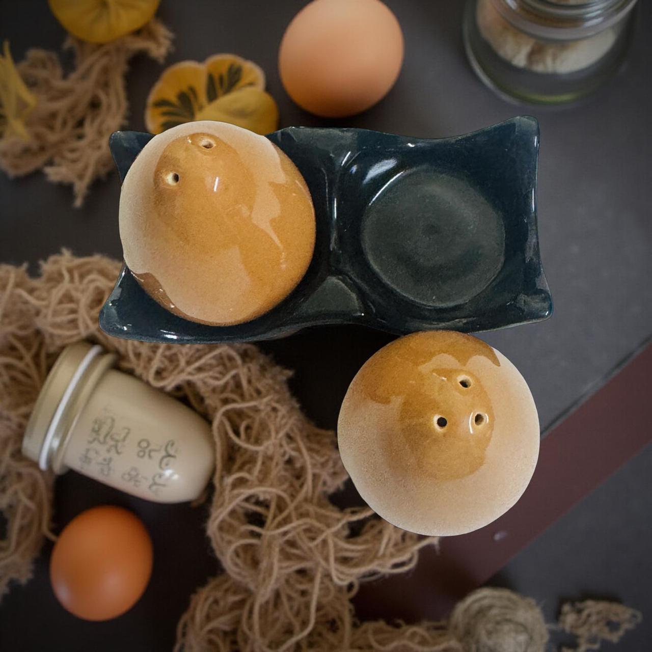 Two ceramic egg-shaped salt and pepper shakers on a textured surface with eggs around.