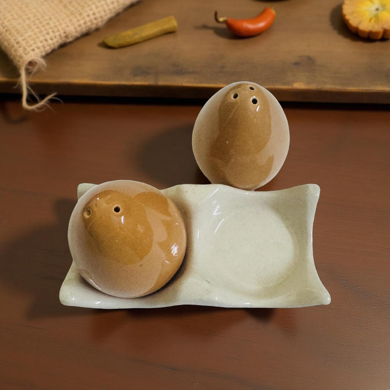 Two ceramic salt andpepper shakes on a perch with a wooden background