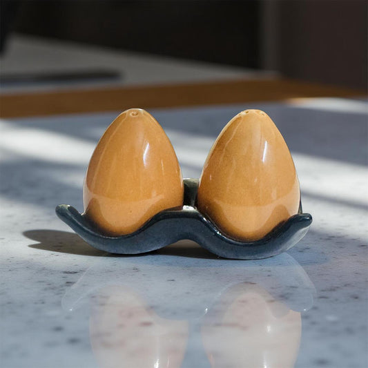 Two brown ceramic items in a black holder on a marble surface