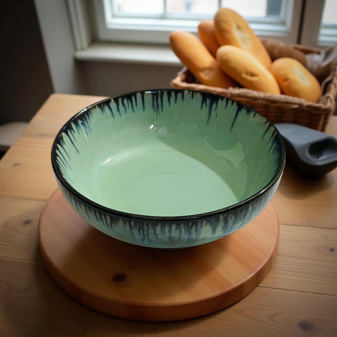 Green ceramic bowl on a wooden stand with bread in the background