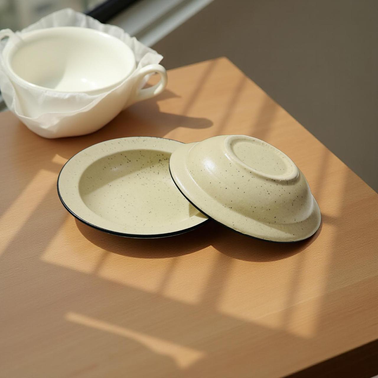 Two ceramic dishes with lids on a wooden surface