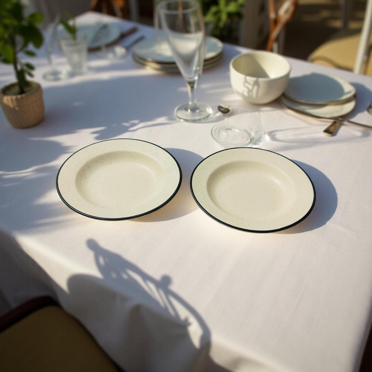 Two ceramic plates on a white tablecloth with glasses and cutlery in the background.