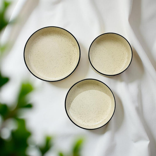 Three ceramic bowls with black rims on a white fabric background