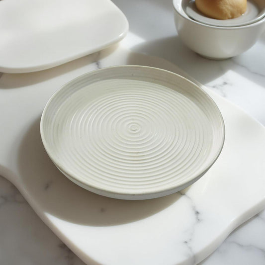 White ceramic plate with textured design on a marble surface