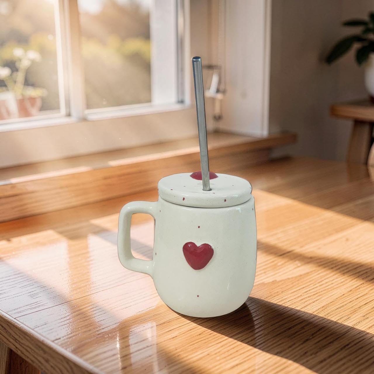White mug with a red heart design on a wooden surface, sunlight streaming through a window.