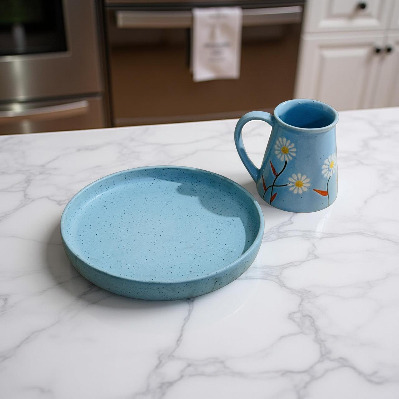Blue ceramic plate and mug on a marble countertop in a kitchen.