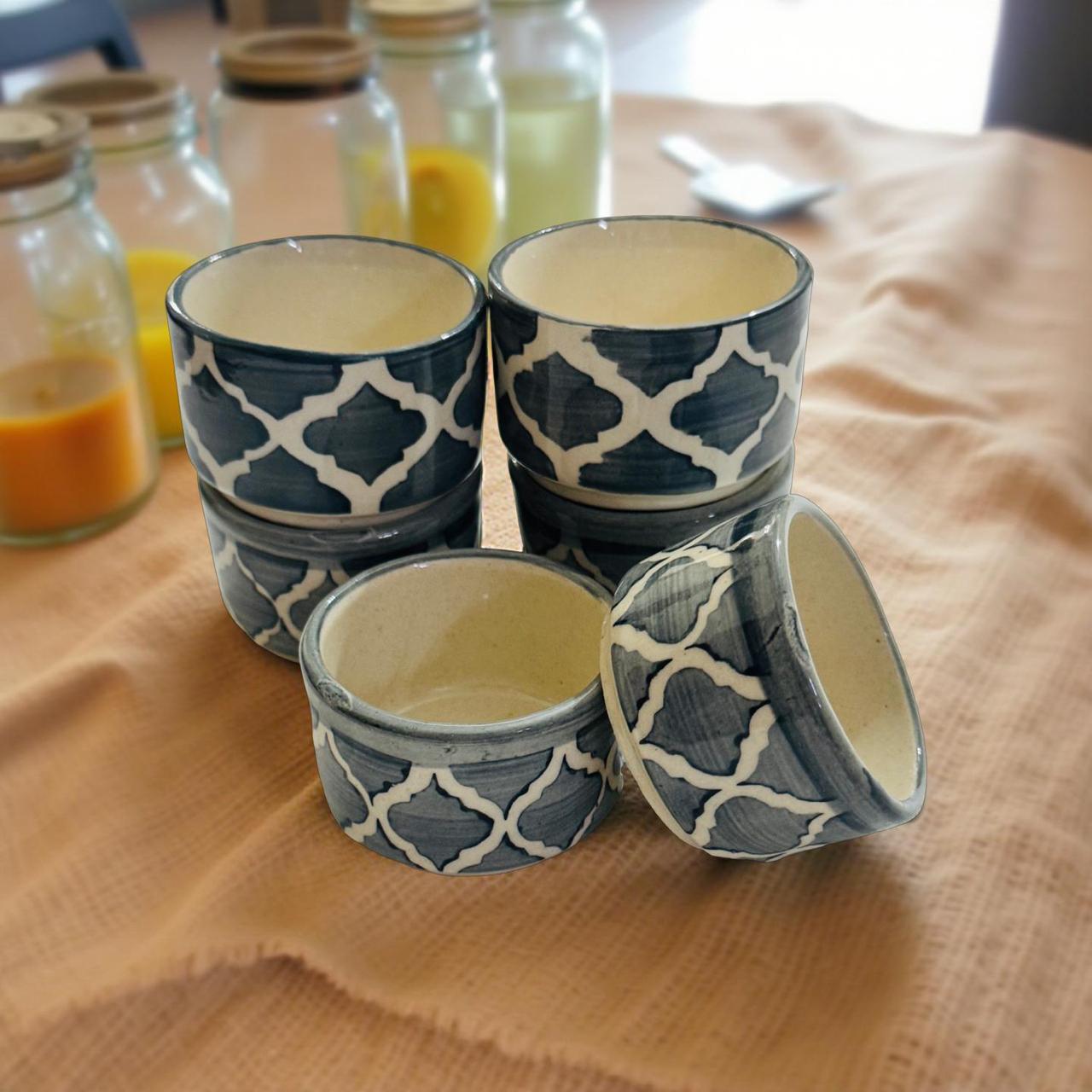 Set of four blue and white patterned ceramic containers on a wooden surface with jars in the background.