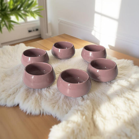 Set of six pink ceramic bowls on a fluffy white rug