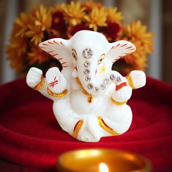 Decorative figure of ganeshji on a red surface with flowers in the background