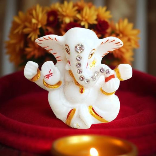 Decorative figure of ganeshji on a red surface with flowers in the background