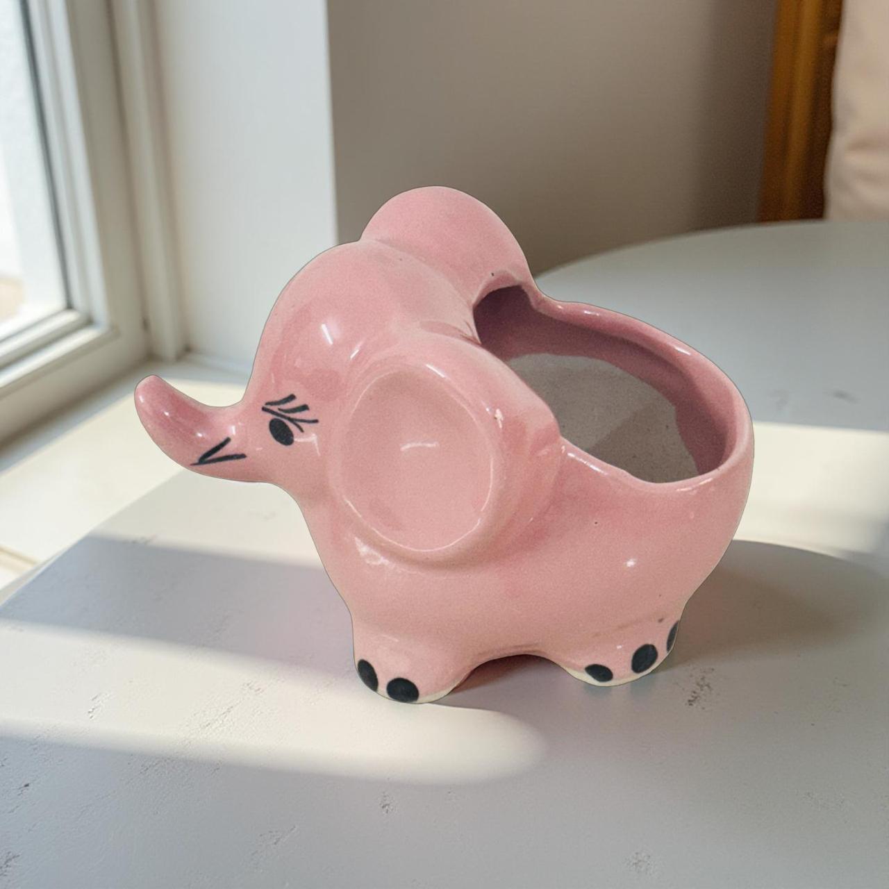 Close-up of hand-painted pink elephant plant pot showing glazed finish and details.