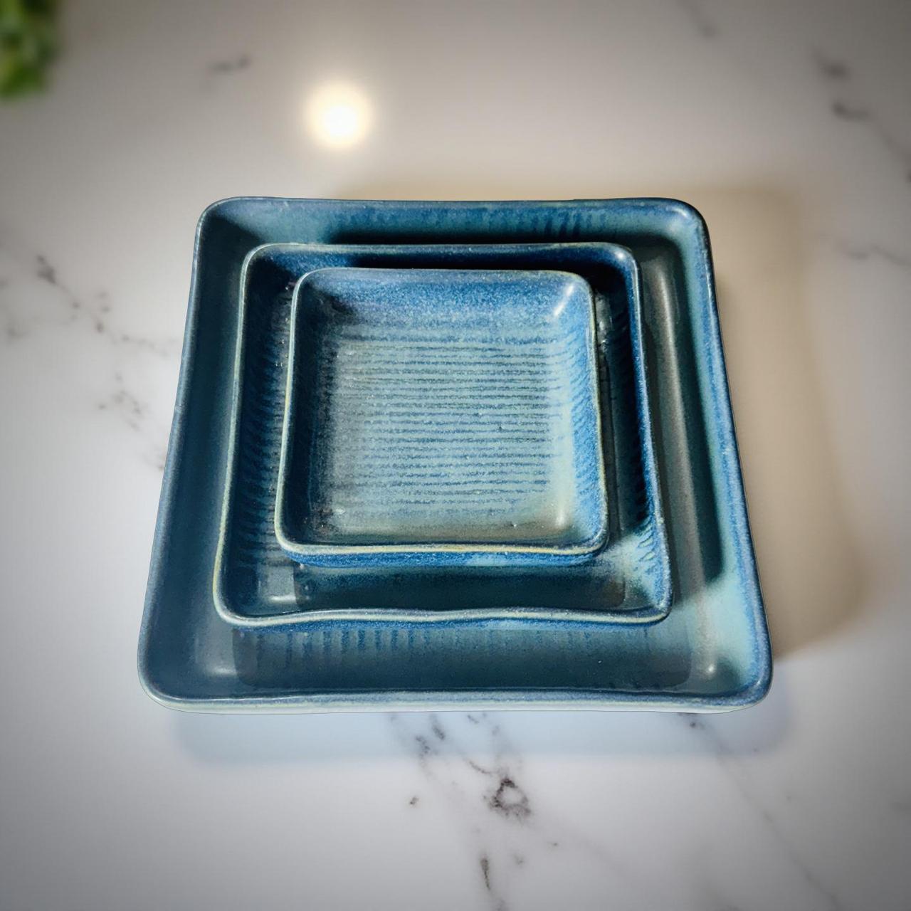 Set of two blue square ceramic trays on a marble surface