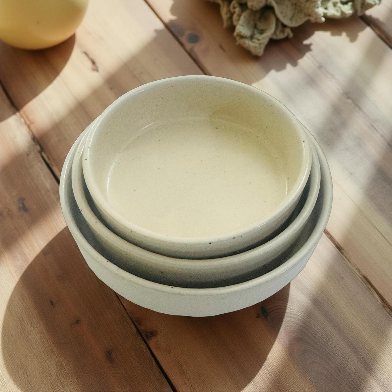 Stack of three ceramic bowls on a wooden surface