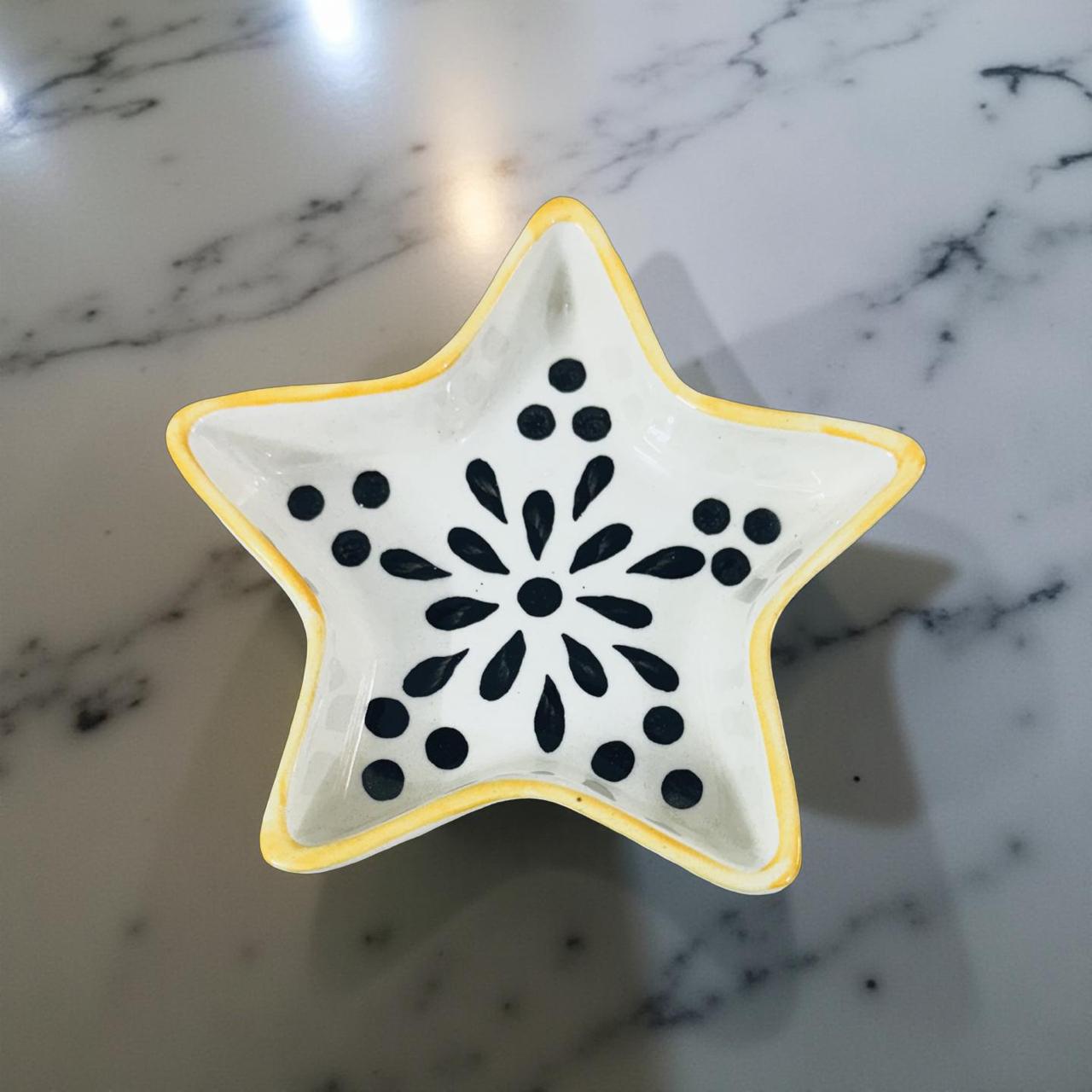 Star-shaped ceramic dish with black pattern on a marble surface