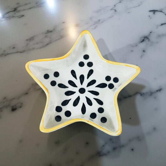 Star-shaped ceramic dish with black pattern on a marble surface