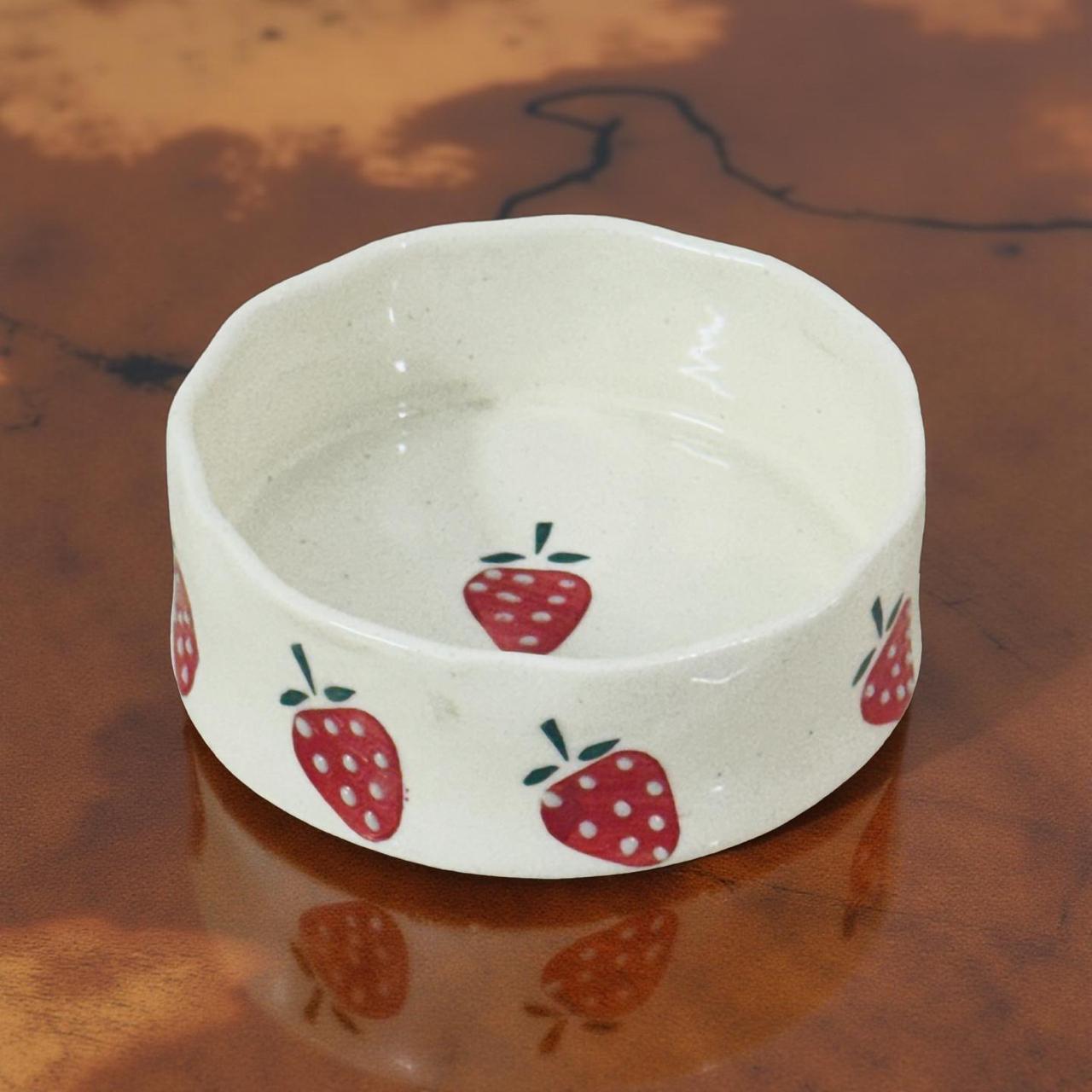 small ceramic snack bowl with strawberry prints kept on a wooden surface