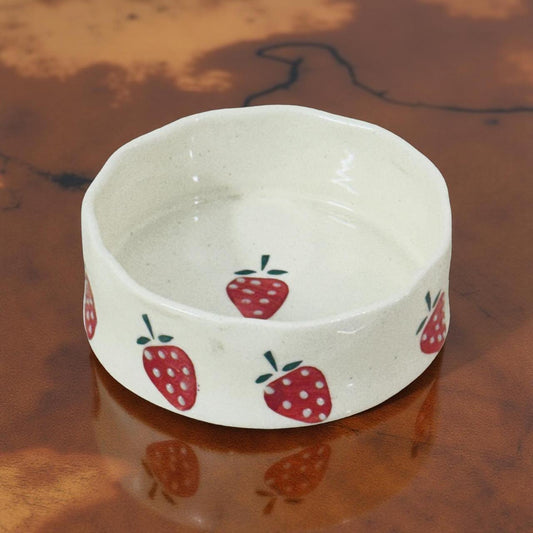 small ceramic snack bowl with strawberry prints kept on a wooden surface