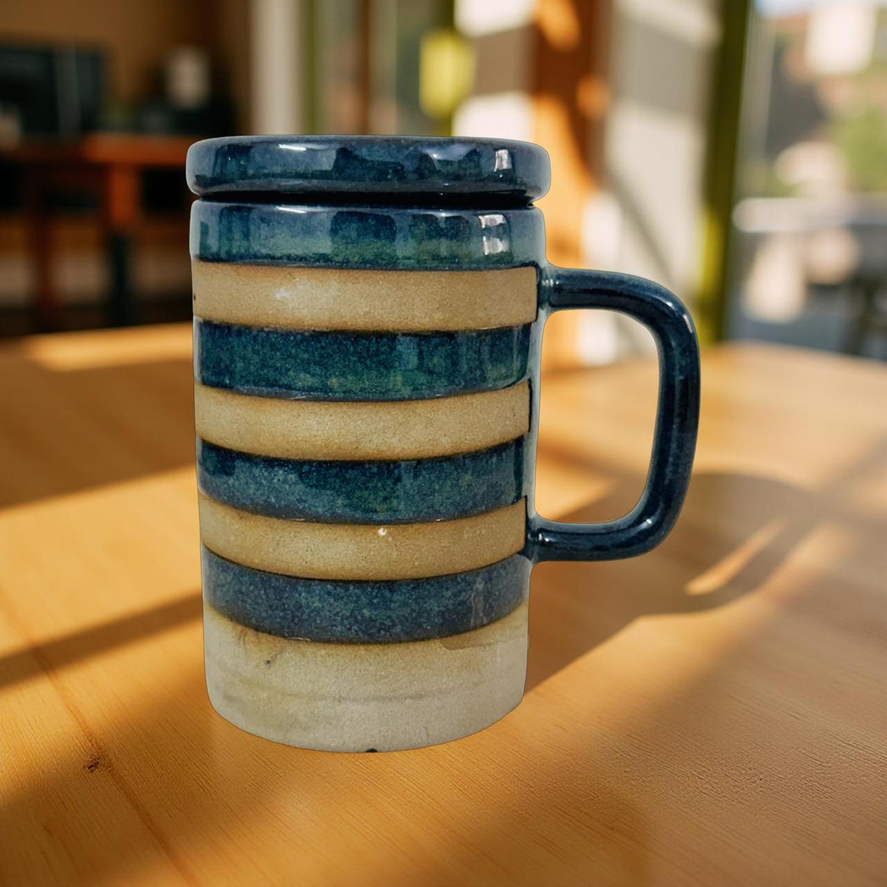 Ceramic mug with blue and beige stripes on a wooden surface