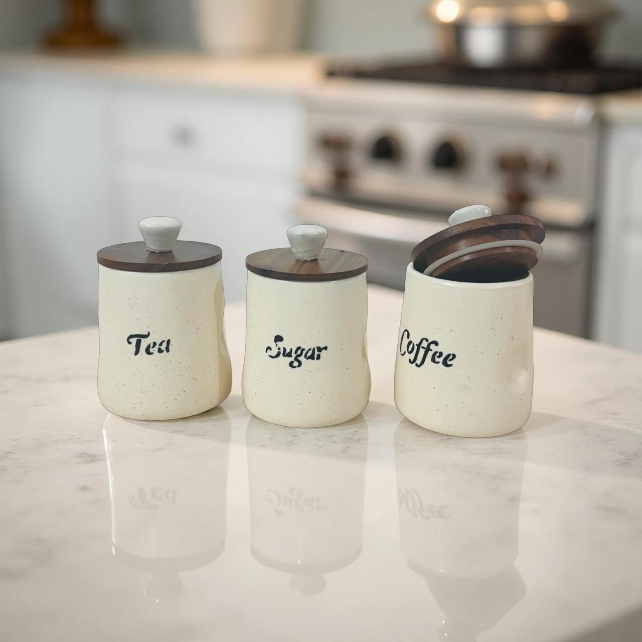 Three ceramic canisters labeled 'Tea', 'Sugar', and 'Coffee' on a kitchen counter.