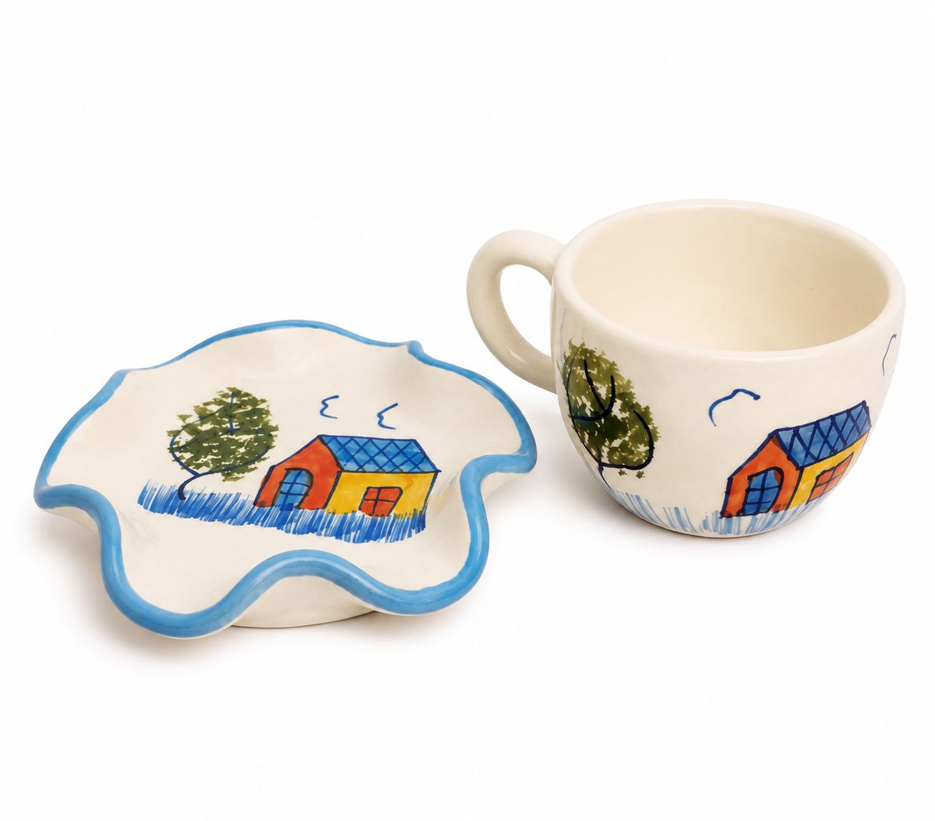 A ceramic cup and matching saucer set, both decorated with a hand-painted rural scene featuring a yellow house with a blue roof, a green tree, and a blue wavy border.