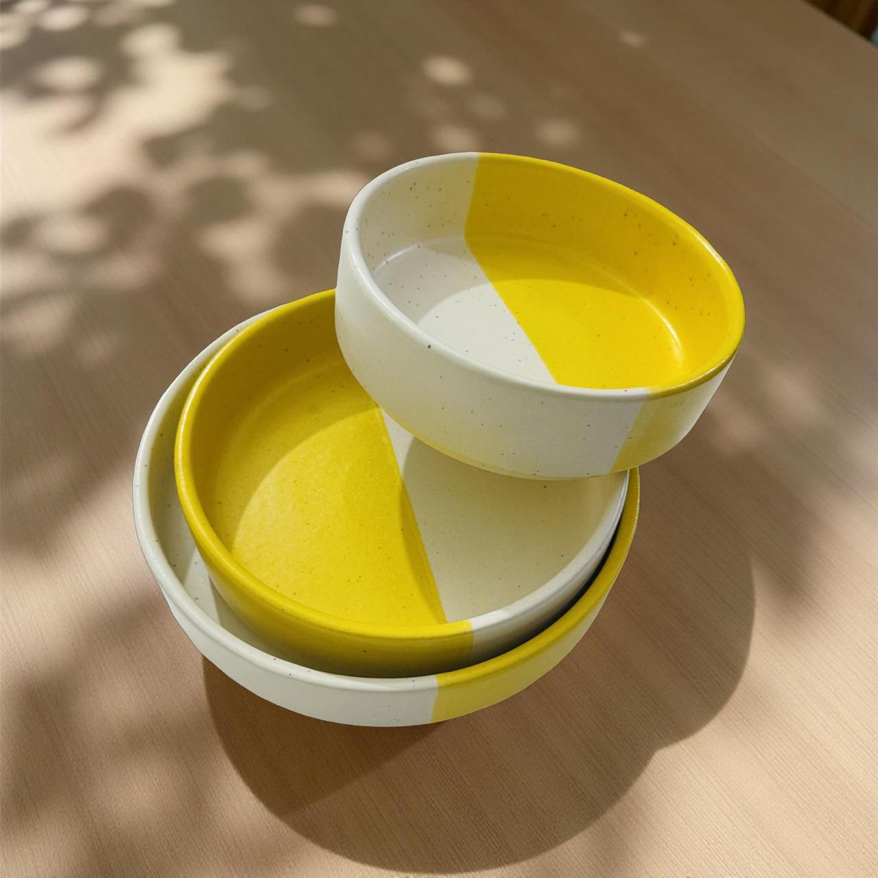 Stack of yellow and white ceramic bowls on a wooden surface with natural light
