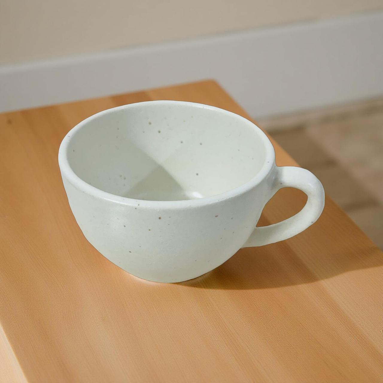 White ceramic cup on a wooden surface with a neutral background