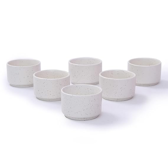 Set of six white ceramic cups with speckled texture on a white background