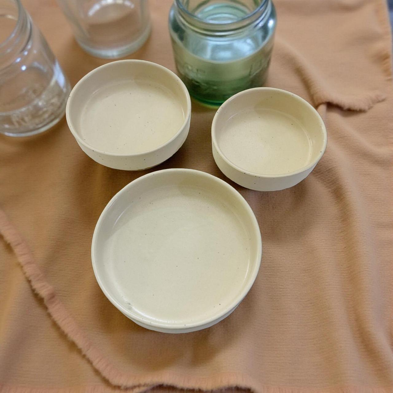 Three ceramic bowls on a textured fabric surface