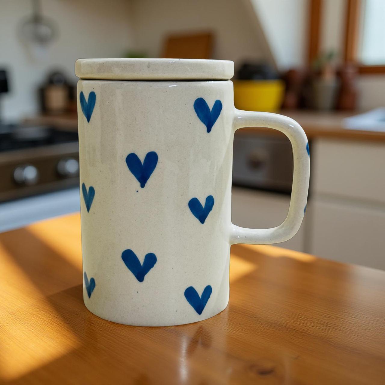 White mug with blue heart patterns on a wooden surface in a kitchen.