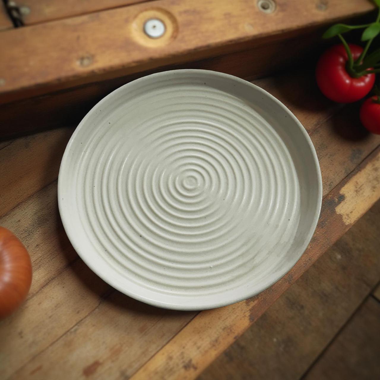 White ceramic plate with textured design on a wooden surface with tomatoes