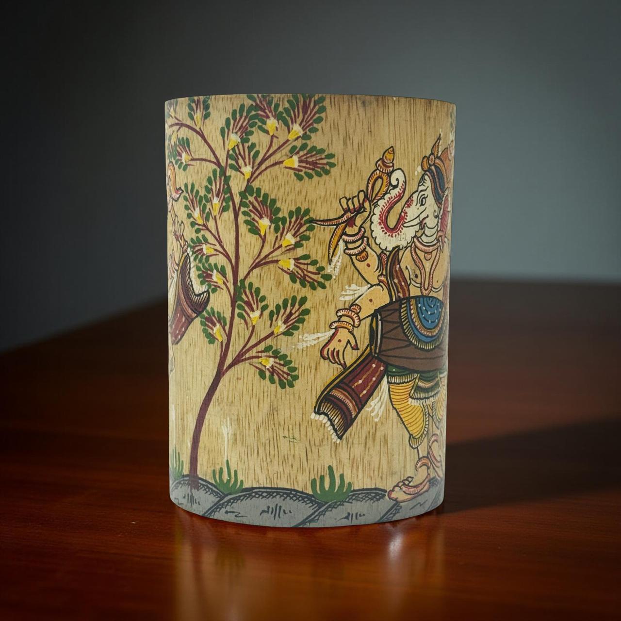 Wooden cutlery holder with hand-painted design of ganeshji and tree on a dark surface