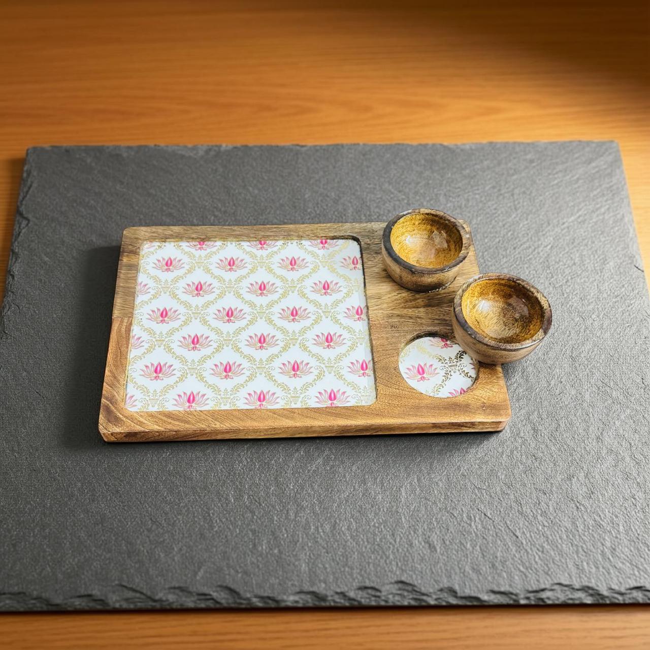 Wooden tray with floral patterned paper and two wooden bowls on a gray slate surface.