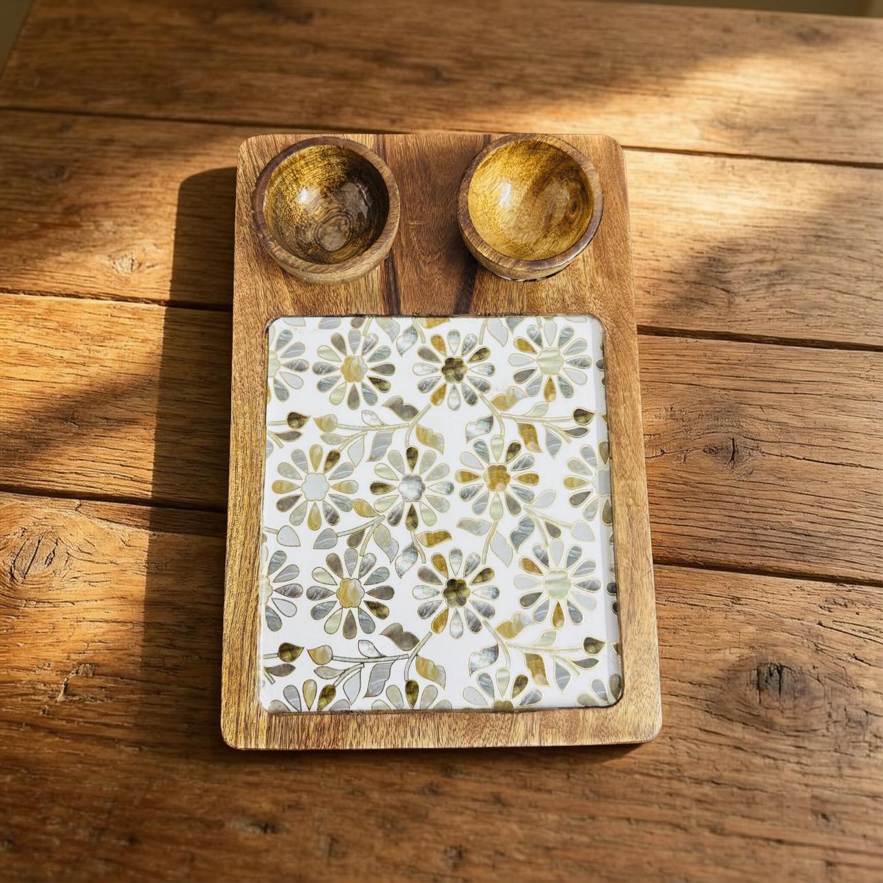Wooden tray with floral-patterned tile and two wooden bowls on a wooden surface